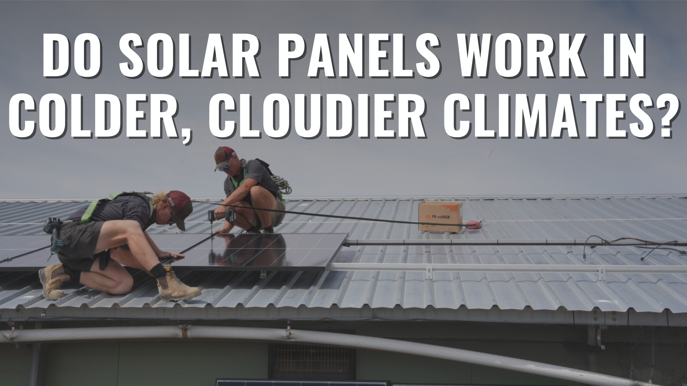 two solar installers on top of a tin roof installing solar panels with clouds in the background