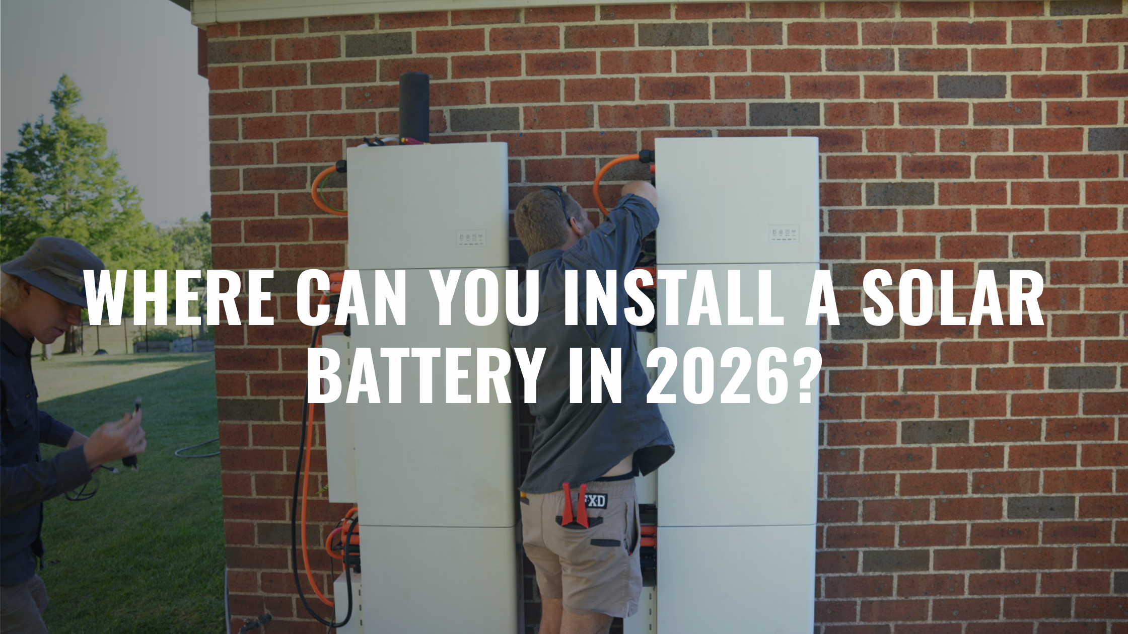 Installers mounting solar batteries on brick wall exterior, illustrating typical residential battery placement in Australia
