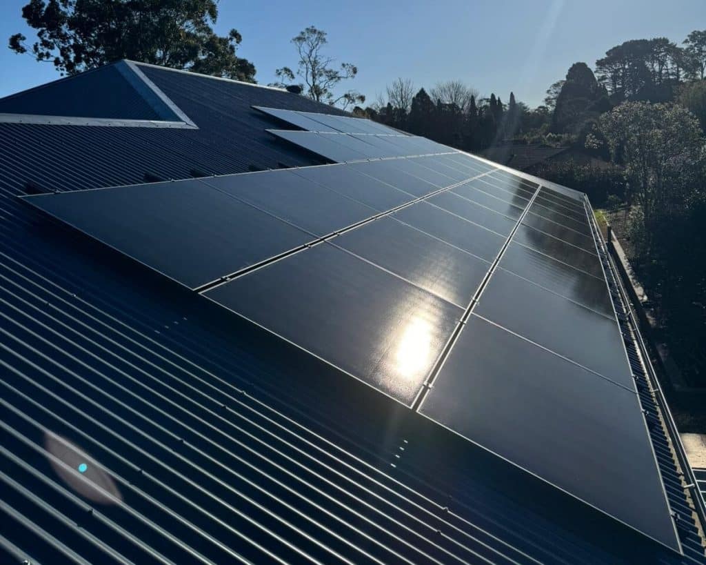 Solar panels installed by Lenergy on top of tin roof with the sun reflecting off