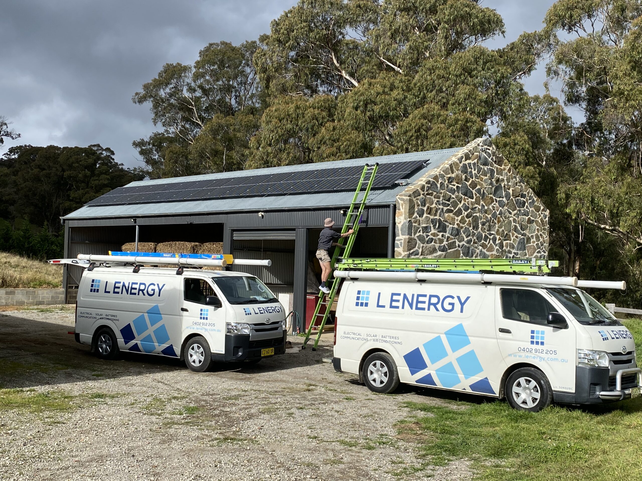 2 Lenergy branded van parked on driveway next to rooftop solar installation
