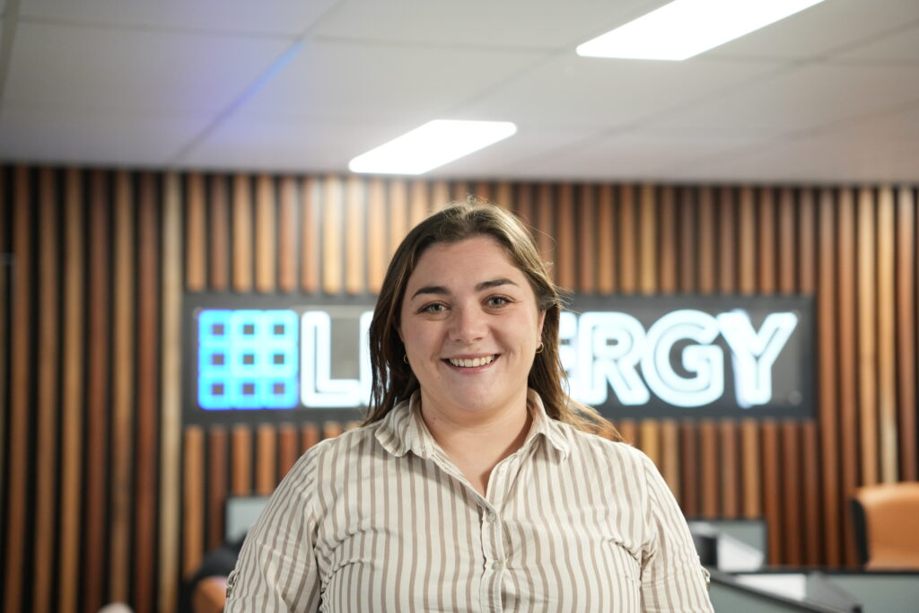 Female Lenergy staff member standing in front of branded Lenergy sign