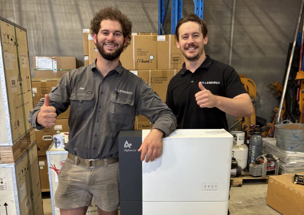 Two Lenergy staff standing with an Alpha ESS battery in Lenergy's HQ and warehouse