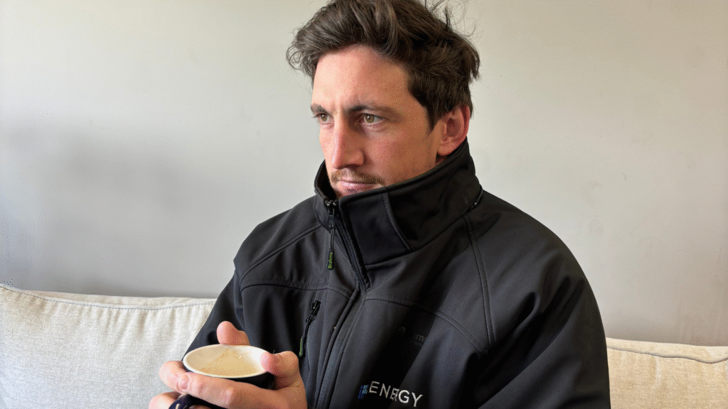 Man holding hot cup of coffee, trying to stay warm and not turn the heater on to save electricity