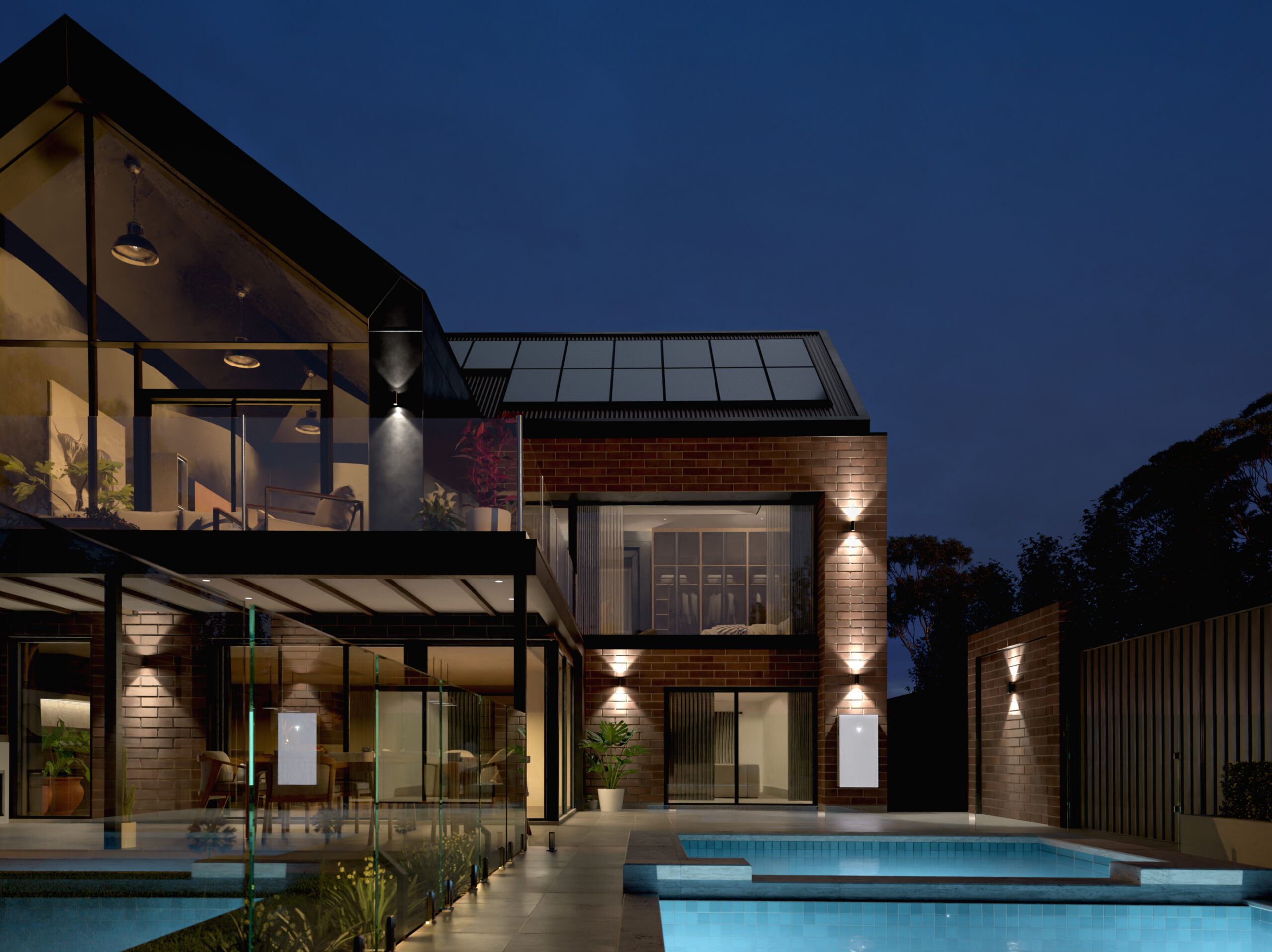 Modern two-storey home at night with solar panels on roof, pool in foreground, and Tesla Powerwall 3
mounted on exterior wall