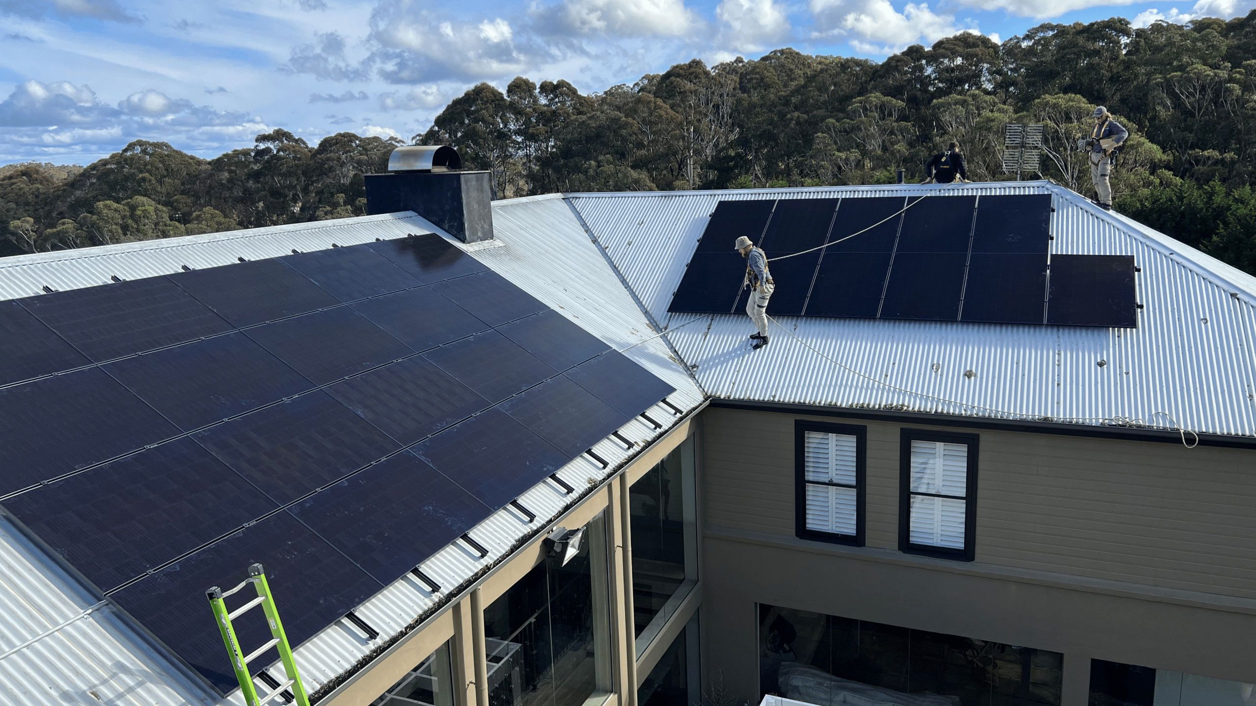 Solar for renters installation team working on a rooftop fitting solar panels under a clear sky.