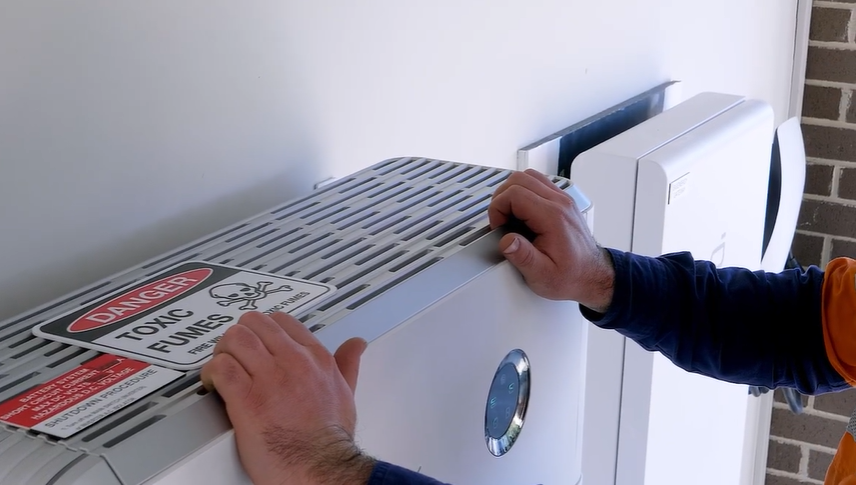 Lenergy technician removing the top plastic cover from a SigenStor inverter to start reconnecting the Sigenergy SigenStor to Wi-Fi.