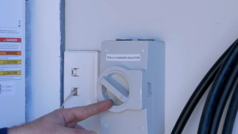 Hand switching off the wall-mounted AC isolator to power cycle the battery when the SigenStor will not reconnect to Wi-Fi.