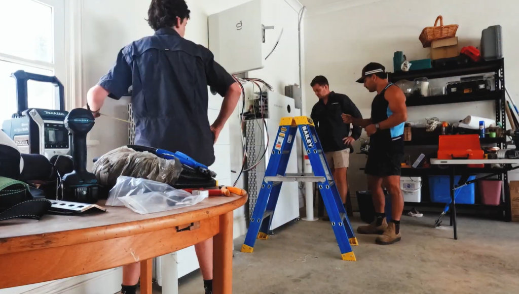 Lenergy technicians installing Colin's home battery in his garage, the storage that lets him run his air conditioner with solar power into the evening.