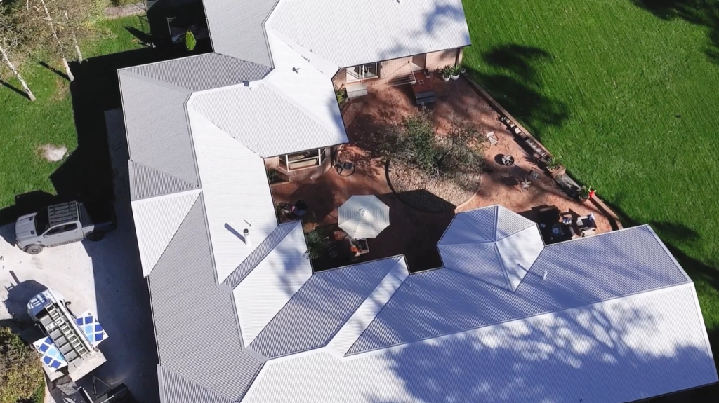 Aerial view of Colin's Goulburn home with its large metal roof, where a rooftop solar and battery system runs his air conditioner with solar power.